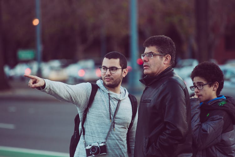 Man In Gray Hoodie Shirt Pointing Finger And Showing Direction To Two People