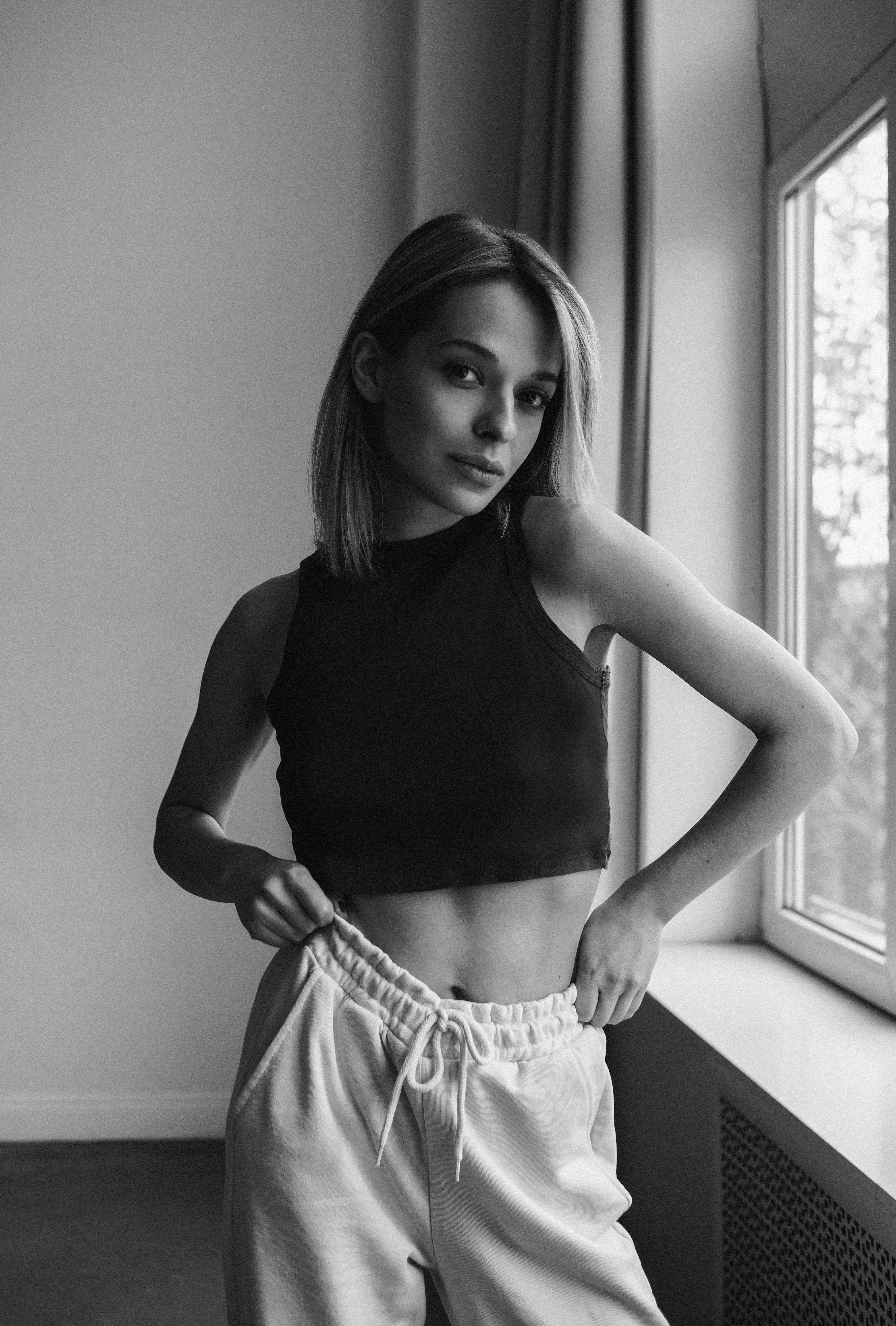 Elegant monochrome portrait of a woman posing indoors by a window.