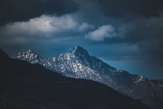 Captivating shot of a snow-covered mountain peak against a dramatic cloudy sky.