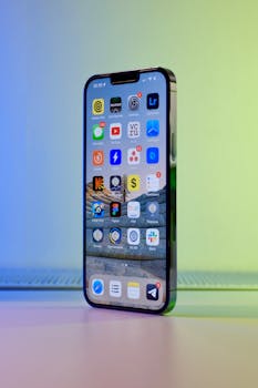 Vertical smartphone display with colorful app icons, standing on a blue and green gradient background.