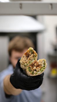 Close-up of a hands holding a chicken burrito with fresh ingredients, perfect for food blogs and menus.
