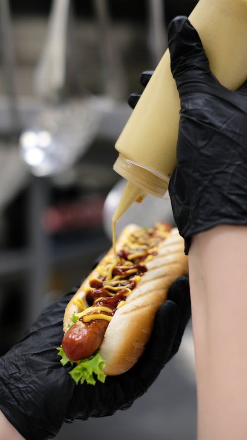 Free Person Pouring Sauce on a Hot Dog  Stock Photo