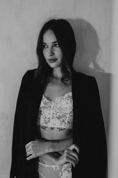 Black and white portrait of a woman in lace lingerie and a blazer, exuding elegance and allure.