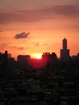 Silhouette of Kaohsiung City skyline at sunset with vibrant sky.