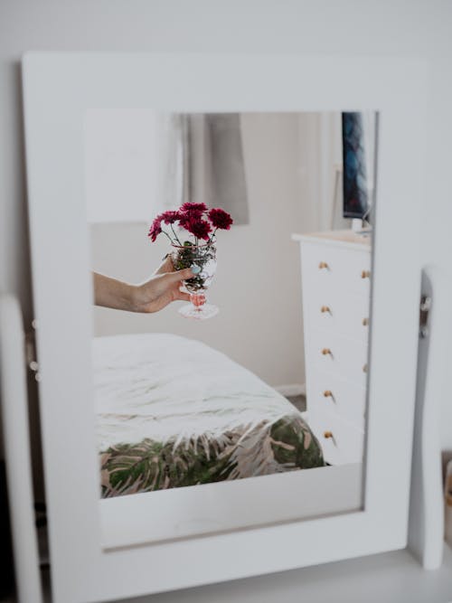 Reflection in a Vanity Mirror of Woman Holding Flowers