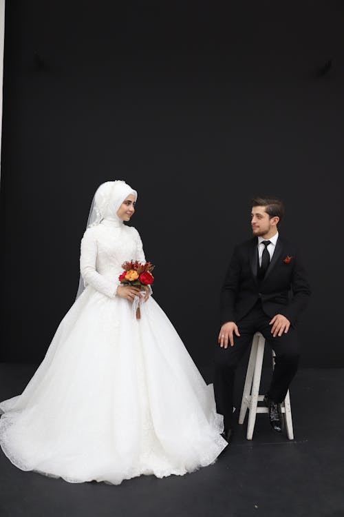 Groom Sitting on Chair Beside Bride in White Wedding Gown Free