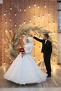 Man and Woman in Wedding Dress Standing on White Floral Arch
