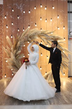 Bride and groom share a romantic dance under ambient lights with a rustic backdrop.
