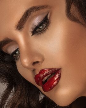 Intense beauty portrait with striking red lips and defined makeup details.