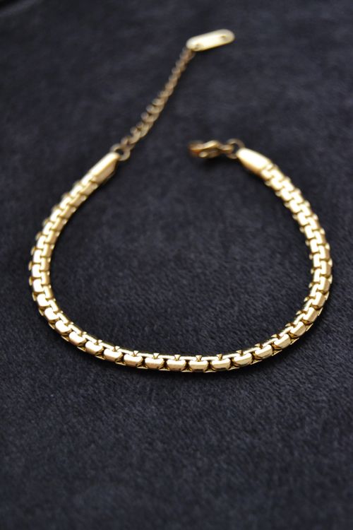 Free Close-up of a gold bracelet on a dark textured surface, showcasing its elegant design. Stock Photo
