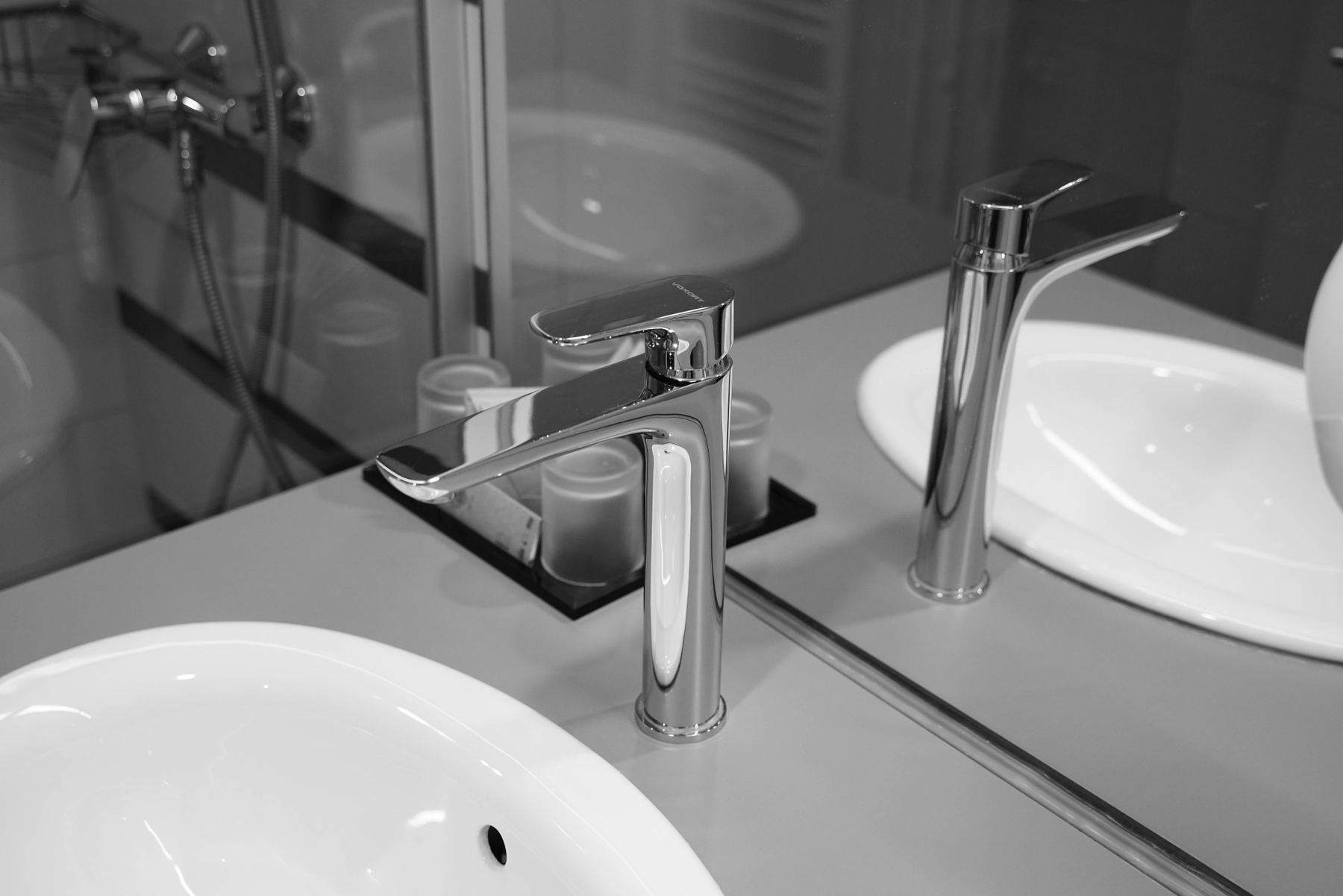 Monochrome bathroom detail with stainless steel faucet and mirror reflection