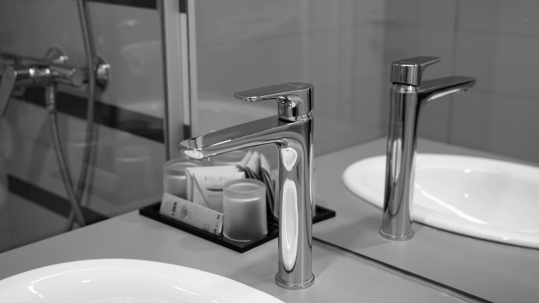 Stylish stainless steel faucet in black and white with mirror reflection in a modern bathroom.