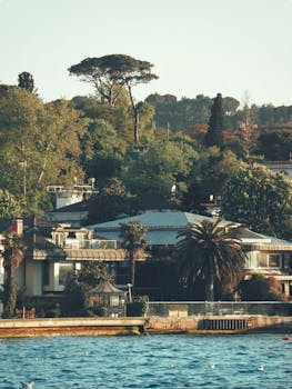 Beautiful villas surrounded by lush trees overlooking a serene waterfront captured on a sunny day.