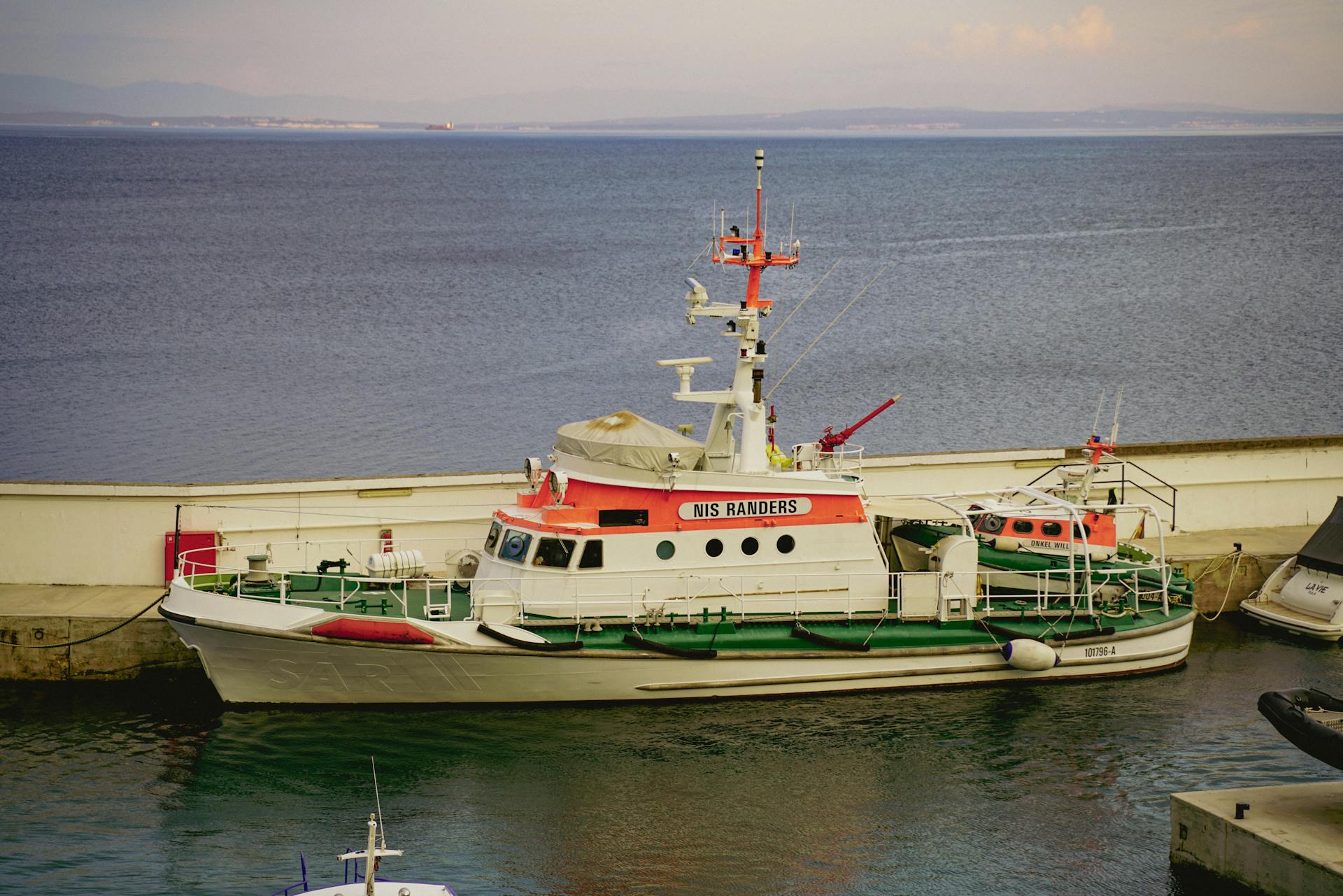 A colorful rescue boat moored at a calm harbor under a serene sky.