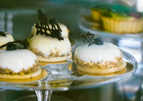 Free Close-up of gourmet pastries with white glaze and chocolate decor on a glass stand. Stock Photo