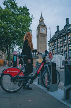 A woman renting a Santander bike near Big Ben, London, showcasing urban mobility and iconic landmarks.