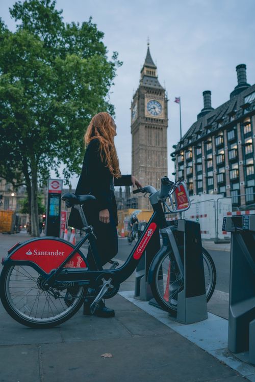 Free A woman renting a Santander bike near Big Ben, London, showcasing urban mobility and iconic landmarks. Stock Photo