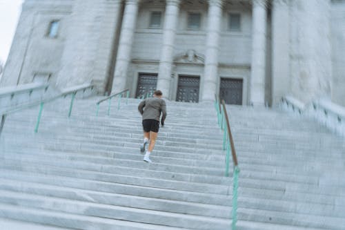 Man in Gray Shirt and Black Shorts Walking Up on Stairs