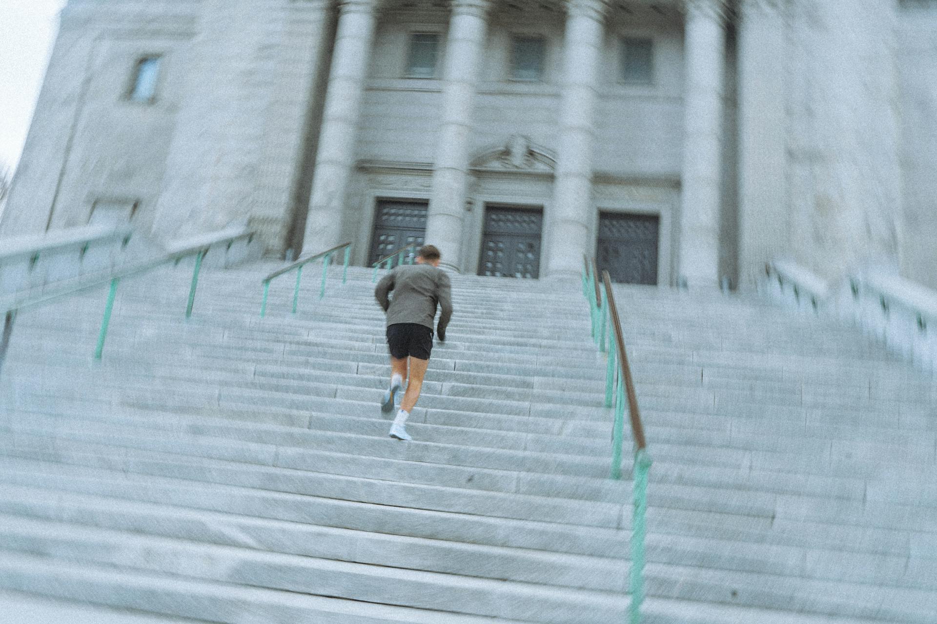 Man in Gray Shirt and Black Shorts Walking Up on Stairs