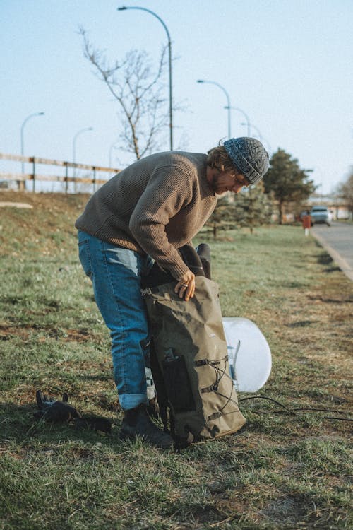 Man Packing Backpack on Roadside