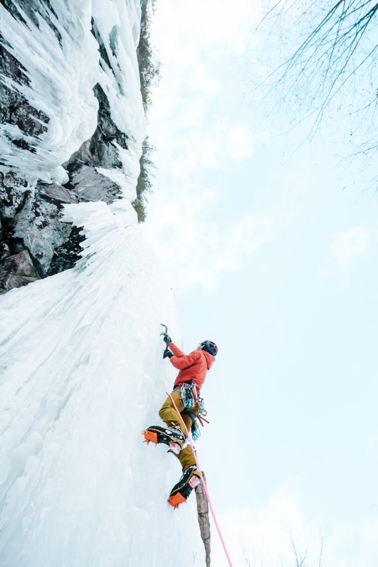 Person Scaling Ice Wall In Mountains