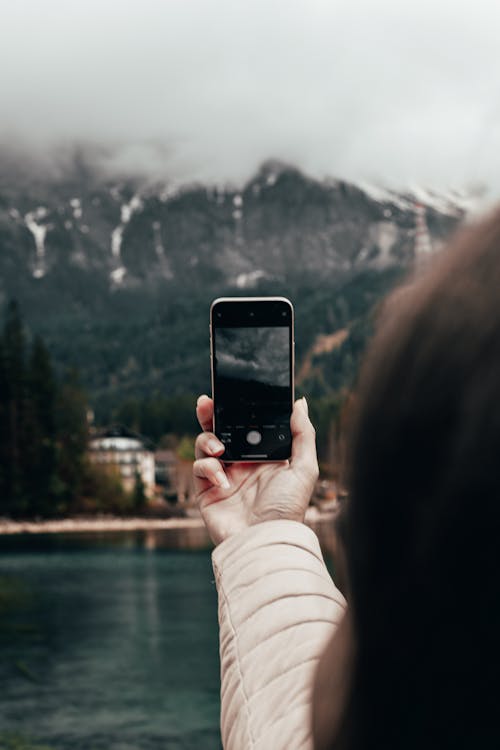 Woman Taking Picture of a Mountain