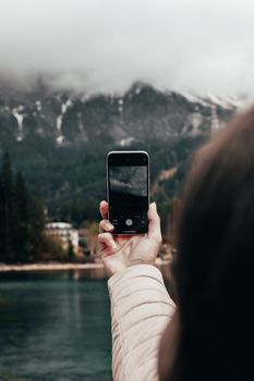 Person photographing misty mountains in Grainau with a smartphone.
