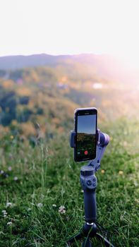 Smartphone on a tripod recording a scenic landscape outdoors.