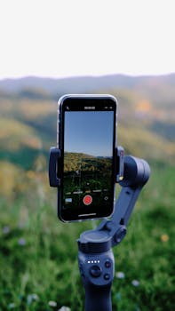 A smartphone mounted on a gimbal recording a video of a beautiful mountain landscape.