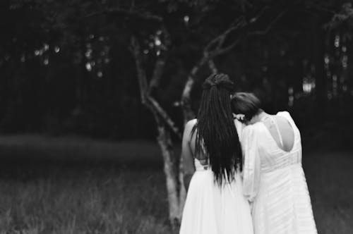 A Grayscale of a Woman Leaning on Another Woman's Shoulder