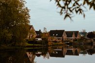 Picturesque residential area in the Netherlands with charming homes reflected in a tranquil lake during autumn.