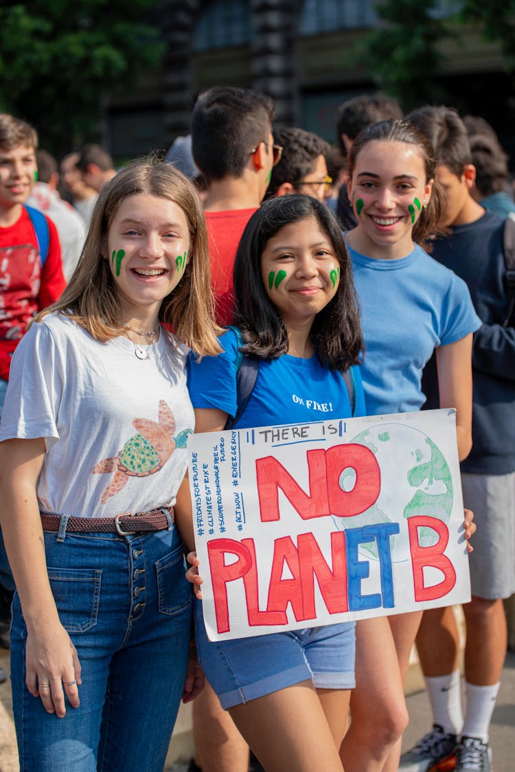 Smiling Girls Posing While Holding A Poster