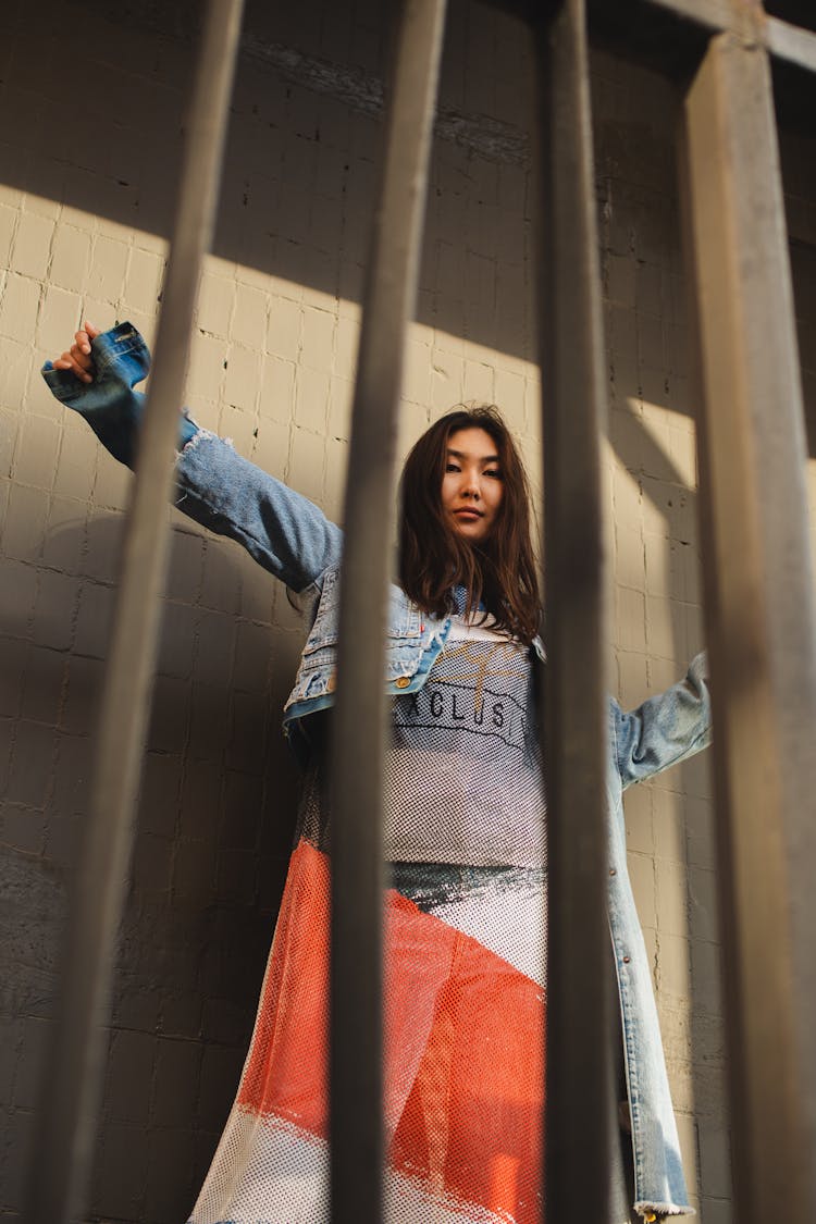 Woman In Jean Jacket Standing Beside A Gray Wall