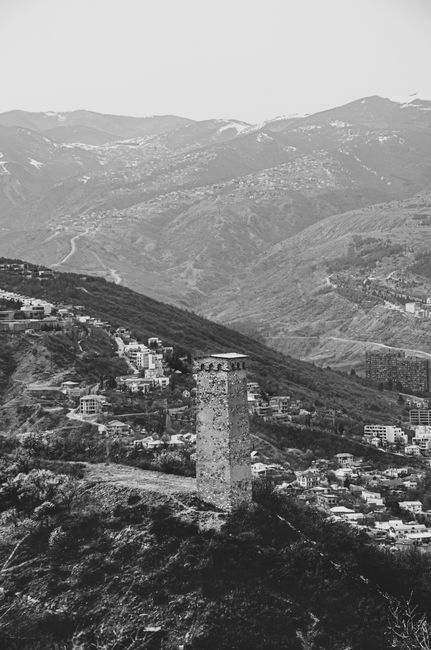 A black and white aerial view of a tower amidst mountainous terrain, capturing the serene and historic essence.