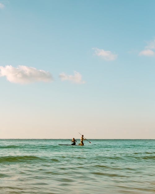 Two People Riding on a Paddleboard on Sea