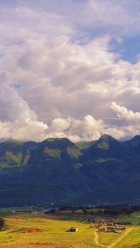 Breathtaking mountain view with rolling clouds above a rural countryside, showcasing natural beauty.