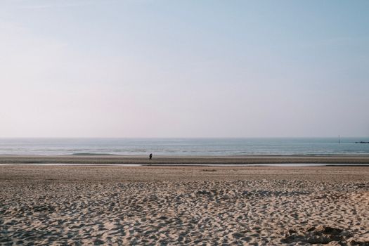 A peaceful beach scene with soft sand and gentle waves under a clear sky.