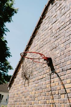 A vintage basketball hoop attached to a rustic brick wall under a clear sky.