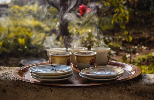 Белые цветочные чайные чашки и блюдца на коричневом деревянном подносе