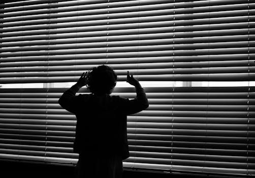 Silhouette Of Child Looking On Window Blinds
