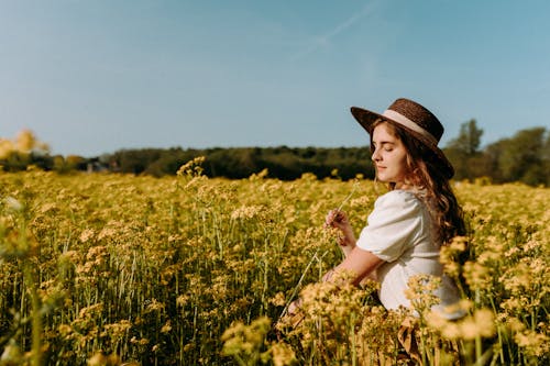Woman in Wide Brim Hat Sitting in Canola Field