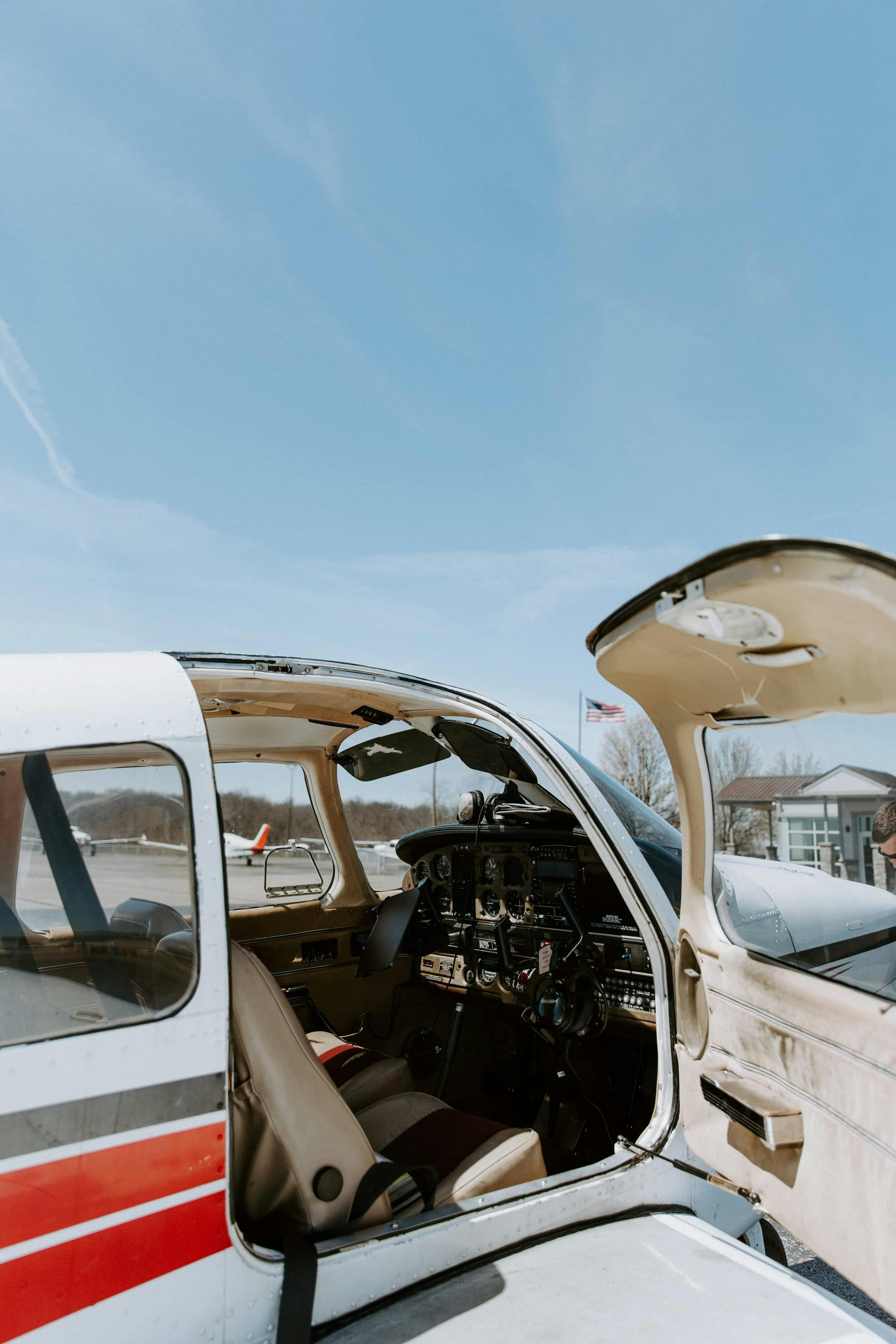 Open cockpit view of a parked small aircraft on a sunny day.
