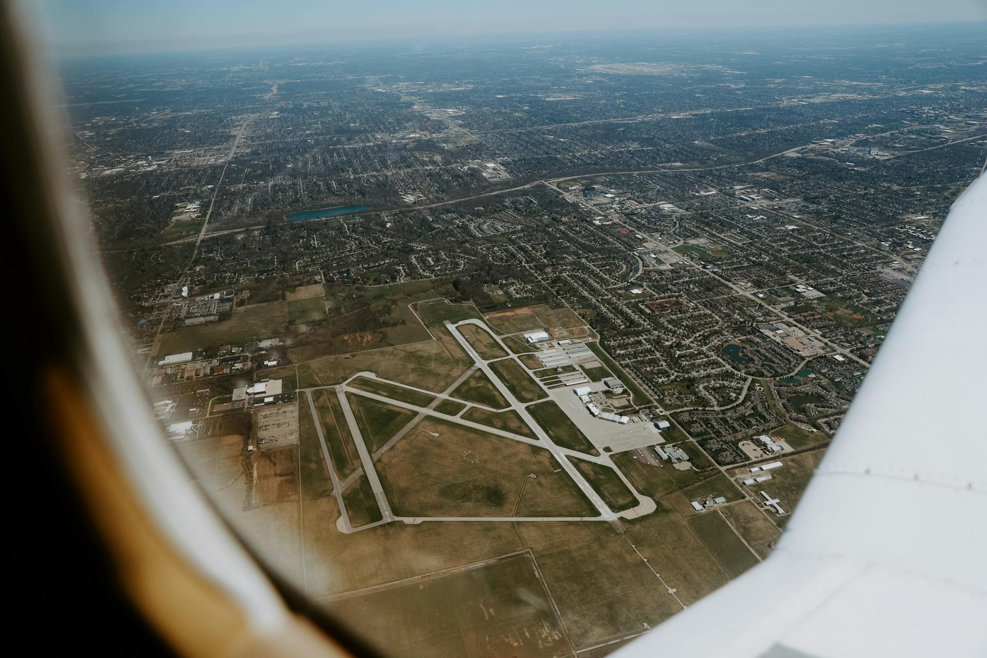 Scenic aerial view of a city with runways from an airplane window, capturing urban layout and infrastructure.