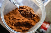 聚焦镜头展示勺子从容器中舀起可可粉，强调其质地