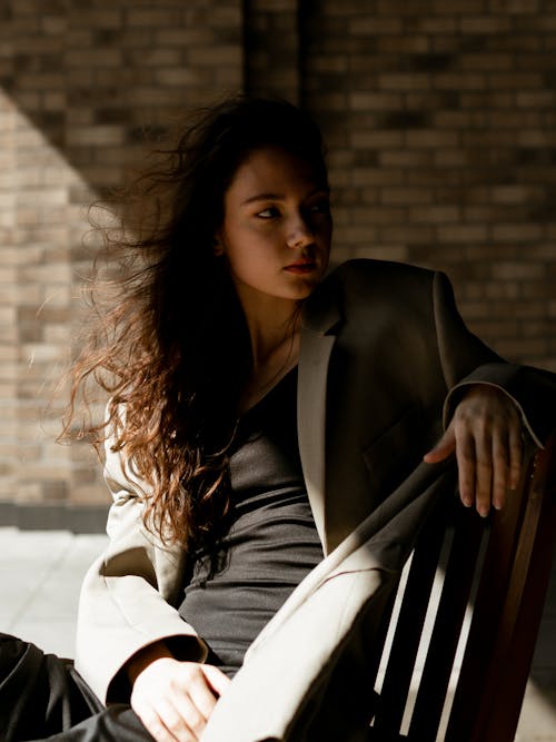 Woman in Gray Blazer Sitting on Brown Wooden Chair