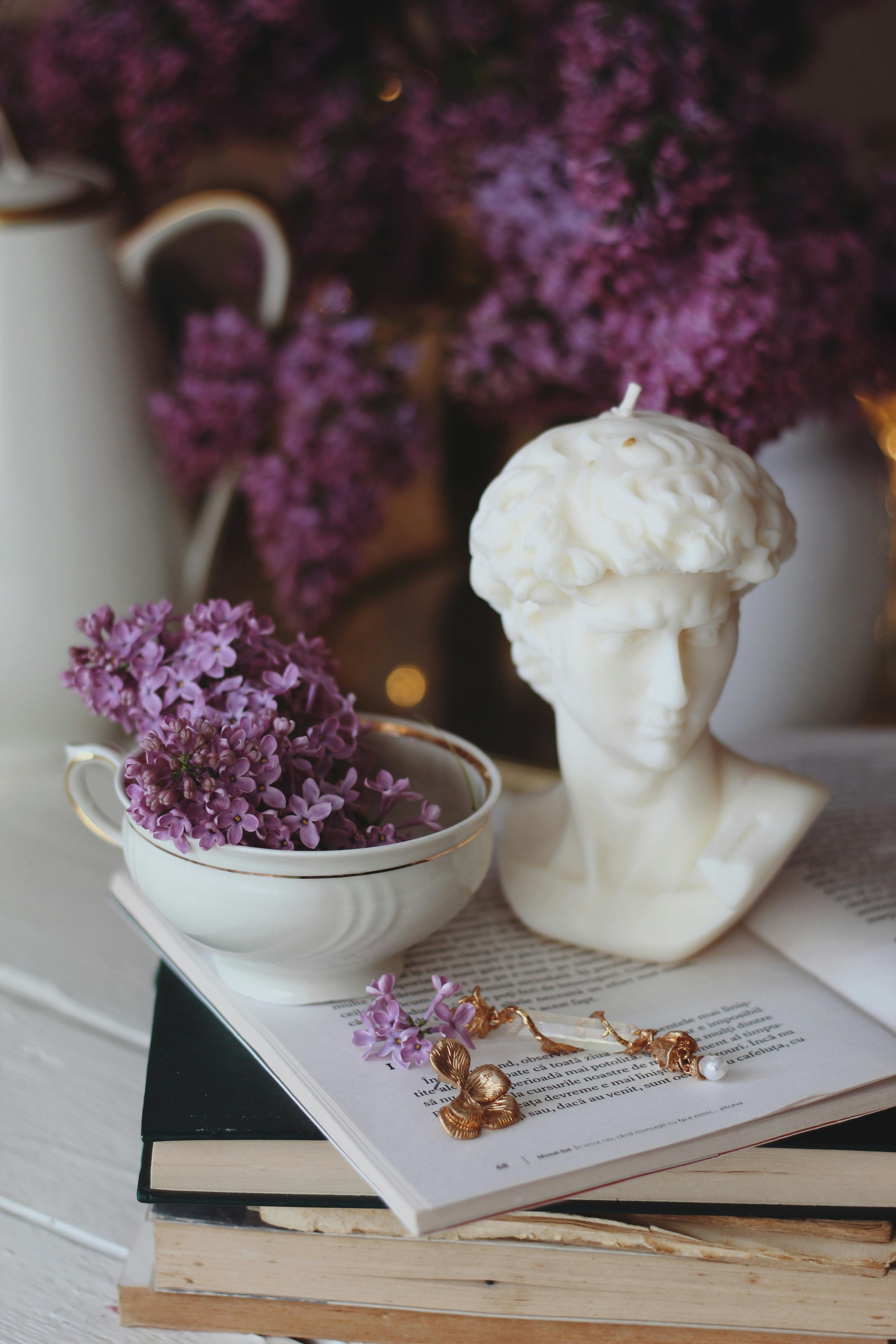 A serene arrangement of lilacs, books, and a bust sculpture, creating a tranquil still life.