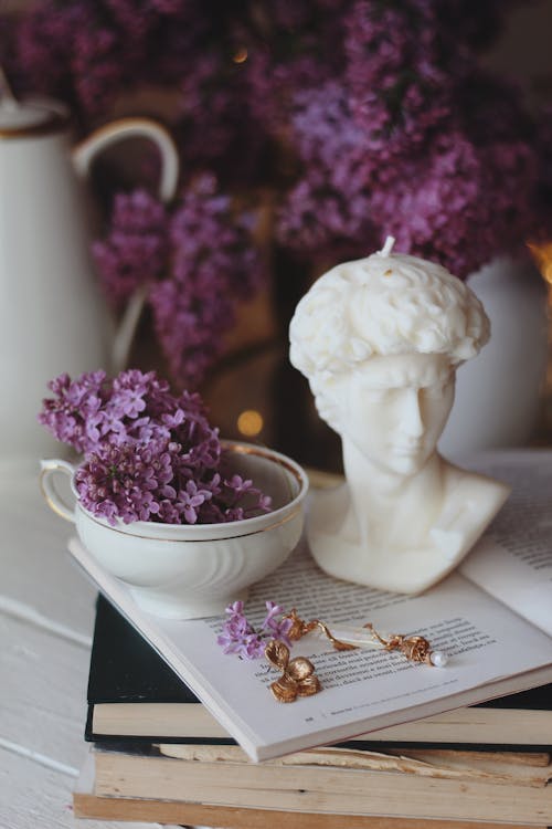 Free Close Up of a Sculpture and Flowers in a Bowl Placed on a Book Stock Photo