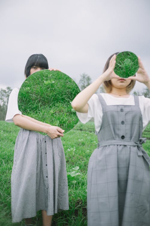 Women Holding Round Mirrors on a Field