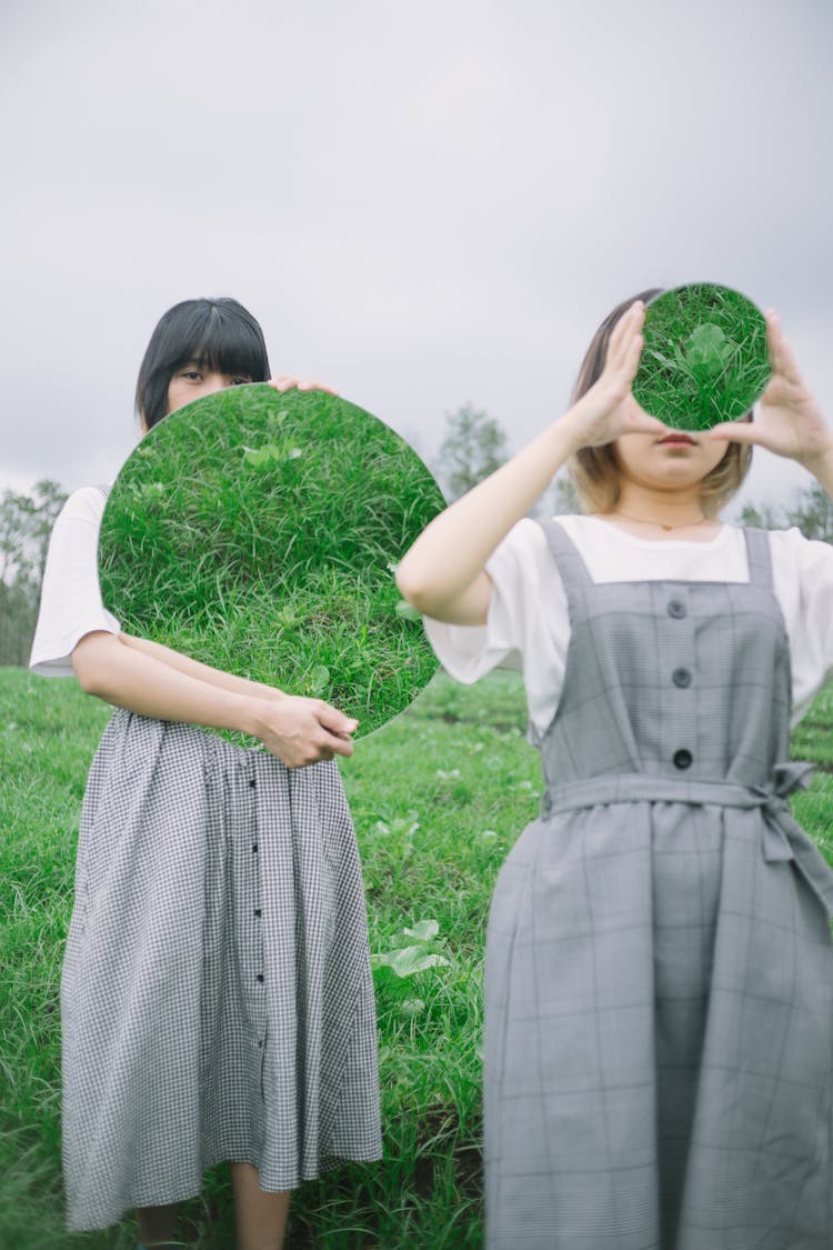 Women Holding Round Mirrors On A Field