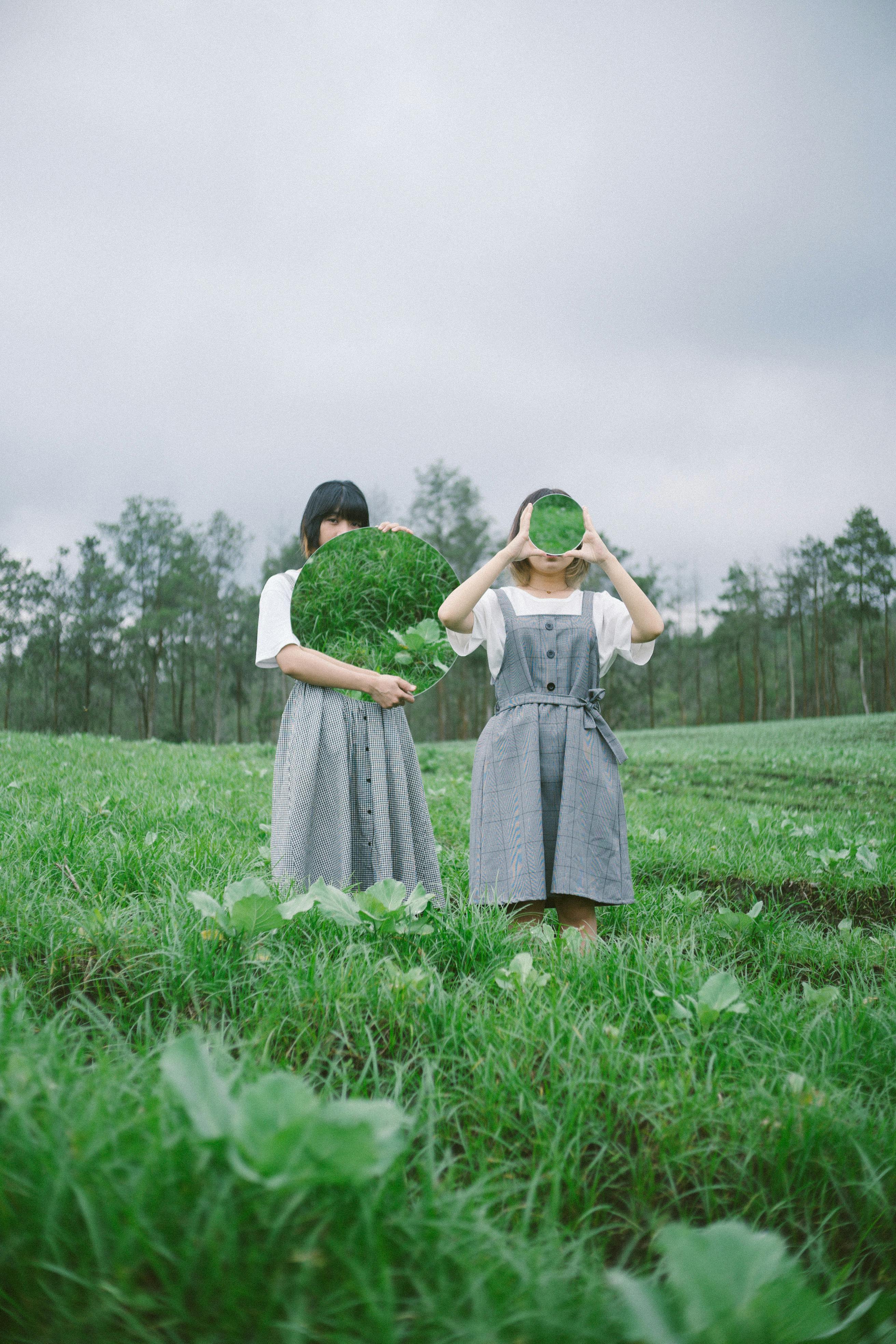 two girls standing in grass field